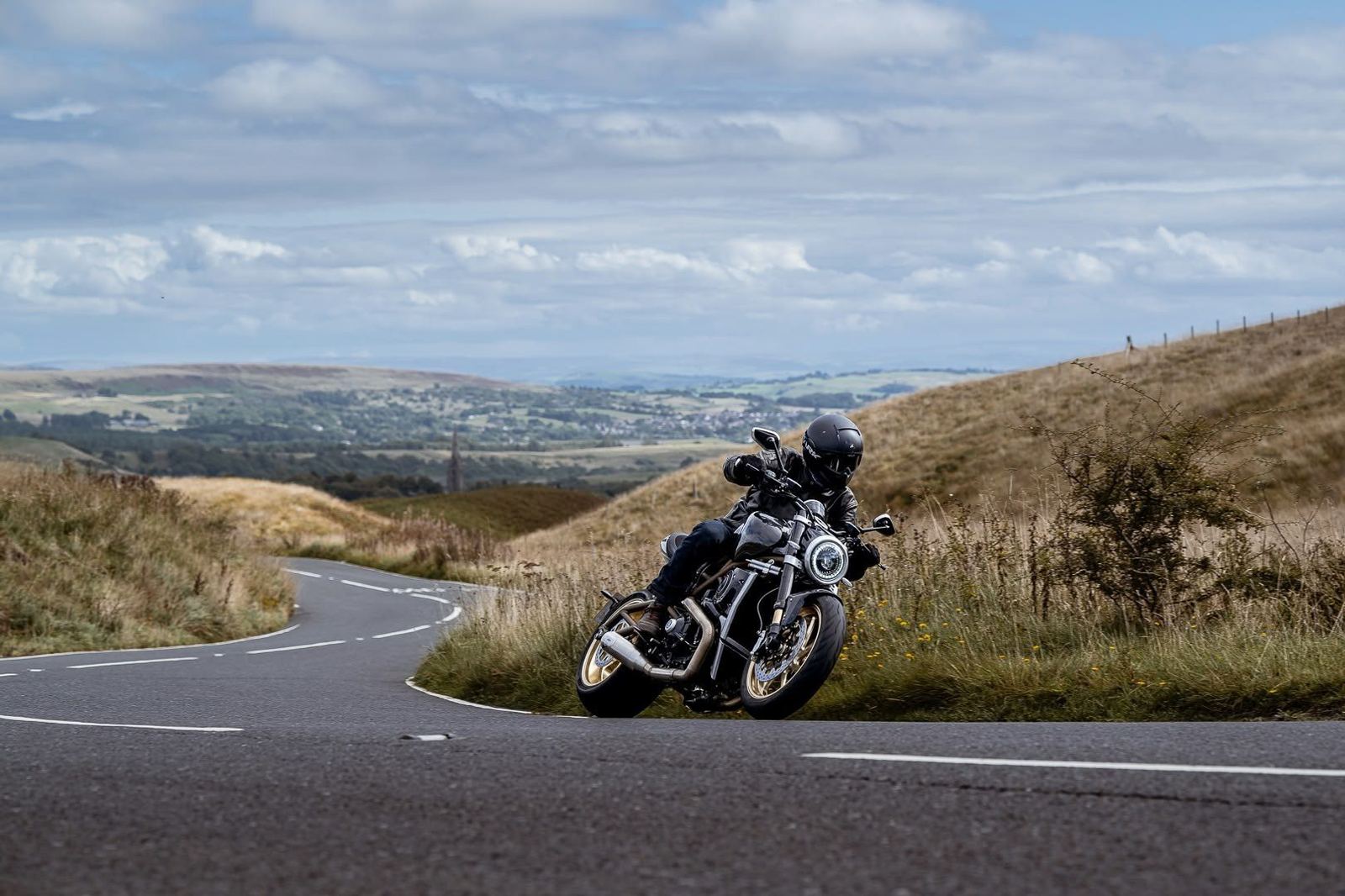 Lightspeed being ridden through a bend on a moorland road